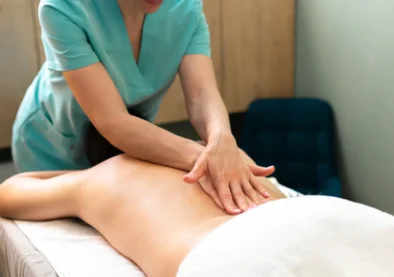 Masajista profesional realizando un masaje en la espalda de un cliente en un ambiente relajante, enfatizando el bienestar y la terapia corporal.